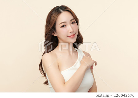 A beautiful young Asian woman with clean, fresh skin against a beige background. Skincare, facial treatment, cosmetology, beauty, and spa. An elegant portrait of an Asian woman. A beautiful young Asian woman with clean, fresh skin against a beige background. Skincare, facial treatment, cosmetology, beauty, and spa. An elegant portrait of an Asian woman. 126042576