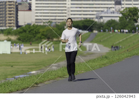 多摩川の土手をランニングする若い男性 126042943