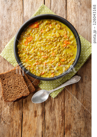 Lentil soup with coconut milk, carrots, onions, turmeric, lemon and ginger close-up in a plate. Vertical top view Lentil soup with coconut milk, carrots, onions, turmeric, lemon and ginger close-up in a plate. Vertical top view 126043168