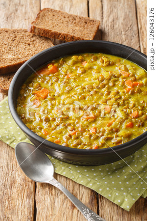 Lentil soup with coconut milk, carrots, onions, turmeric, lemon and ginger close-up in a plate. Vertical 126043176