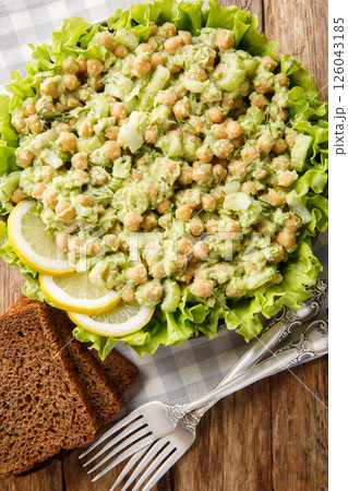 Chickpea Salad made with creamy avocado, celery, onion and herbs closeup on the plate. Vertical top view 126043185