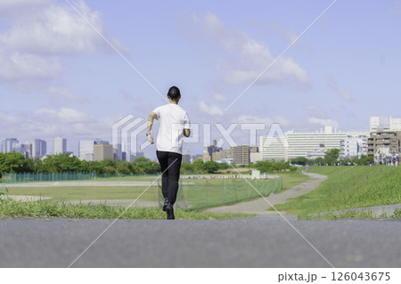 多摩川の土手をランニングする若い男性の後ろ姿 126043675