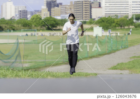 多摩川の土手をランニングする若い男性 126043676