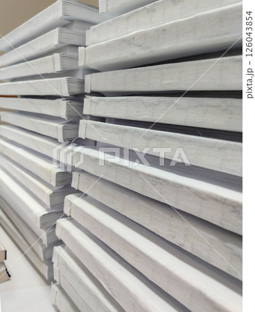 Close-up, a stack of glued book blocks prepared for binding in a printing house, vertical Close-up, a stack of glued book blocks prepared for binding in a printing house, vertical 126043854