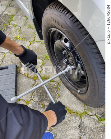 Nitra, Slovakia - 08.05.2025: Car repair. Wheel replacement. Seasonal tire change. The mechanic removes the wheel with both hands and a wrench. 126045084