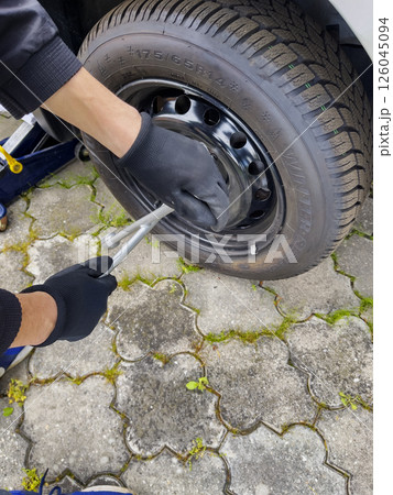 Nitra, Slovakia - 08.05.2025: Car service. Wheel replacement. Seasonal tire change. The mechanic removes the wheel with both hands and a key. Nitra, Slovakia - 08.05.2025: Car service. Wheel replacement. Seasonal tire change. The mechanic removes the wheel with both hands and a key. 126045094
