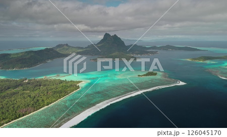 Stunning aerial view of Bora Bora island showing the turquoise lagoon, reef barrier, and lush greenery under a cloudy sky in French Polynesia. Travel tropical vacation concept. Natural background 126045170