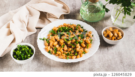 Warm salad of white fried beans and parsley on a plate on the table web banner 126045829
