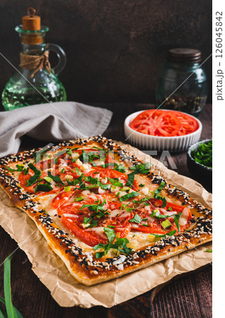 Appetizing galette with tomatoes, cheese and herbs on the table verical view Appetizing galette with tomatoes, cheese and herbs on the table verical view 126045842