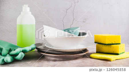 Stack of plates in foam, cloth, sponges, gloves and detergent on table web banner Stack of plates in foam, cloth, sponges, gloves and detergent on table web banner 126045858