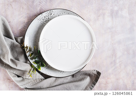 Pair of empty ceramic plates with napkin on gray background top view 126045861