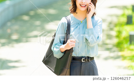 遊歩道を歩きながらスマートフォンで話す笑顔の女性・ビジネスウーマン 126046257