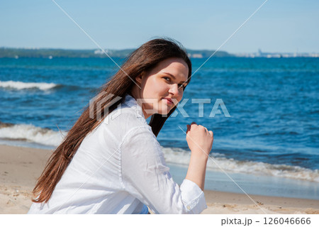 Young caucasian female enjoying a sunny day at the beach with clear blue skies and ocean waves creating a serene and relaxing backdrop. Digital nomad lifestyle. Remote work Young caucasian female enjoying a sunny day at the beach with clear blue skies and ocean waves creating a serene and relaxing backdrop. Digital nomad lifestyle. Remote work 126046666
