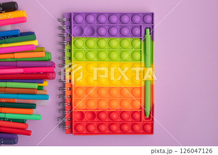 Pencil case with school supplies with notebook on purple background. Top view. Copy space Pencil case with school supplies with notebook on purple background. Top view. Copy space 126047126