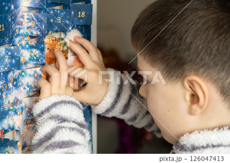 A child takes out a small chocolate from a Christmas advent calendar A child takes out a small chocolate from a Christmas advent calendar 126047413