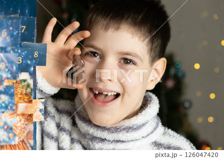 A little boy holding a chocolate Santa figurine from the advent calendar in his hands A little boy holding a chocolate Santa figurine from the advent calendar in his hands 126047420