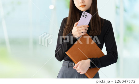 スマートフォンとバインダーを持つ若い女性・ビジネスウーマン スマートフォンとバインダーを持つ若い女性・ビジネスウーマン 126047572