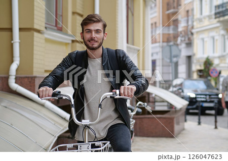 Handsome bike messenger with backpack stands near bicycle and look at camera 126047623