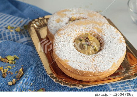 Shortbread dough biscuits with pistachio cream and nuts on gold paper plate. Dessert for party, celebration. Shortbread dough biscuits with pistachio cream and nuts on gold paper plate. Dessert for party, celebration. 126047865