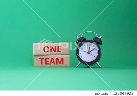One Team symbol. Concept word One Team on wooden blocks. Beautiful green background with alarm clock. Business and One Team concept. Copy space One Team symbol. Concept word One Team on wooden blocks. Beautiful green background with alarm clock. Business and One Team concept. Copy space 126047922