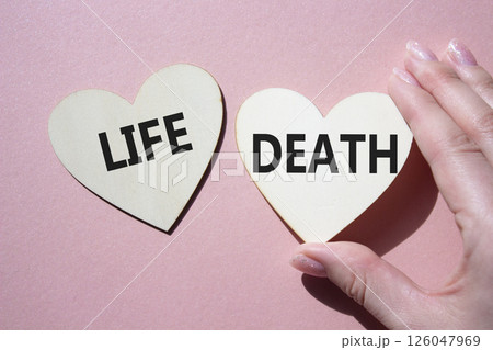 Life or Death symbol. Concept word Life or Death on wooden hearts. Businessman hand. Beautiful pink background. Business and Life or Death concept. Copy space Life or Death symbol. Concept word Life or Death on wooden hearts. Businessman hand. Beautiful pink background. Business and Life or Death concept. Copy space 126047969