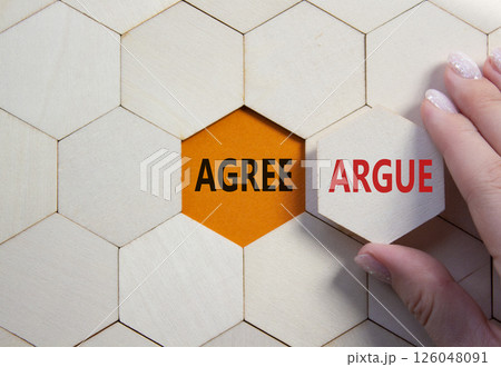 Agree or Argue symbol. Concept word Agree or Argue on wooden comb puzzle. Businessman hand. Beautiful orange background. Business and Agree or Argue concept. Copy space Agree or Argue symbol. Concept word Agree or Argue on wooden comb puzzle. Businessman hand. Beautiful orange background. Business and Agree or Argue concept. Copy space 126048091