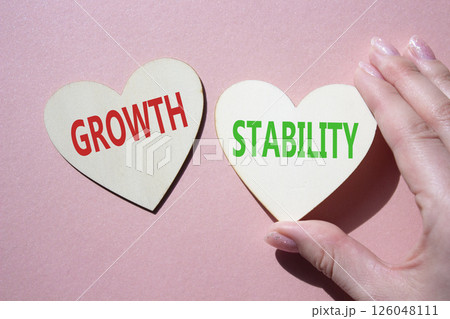 Growth and Stability symbol. Concept word Growth and Stability on wooden hearts. Businessman hand. Beautiful pink background. Business and Growth and Stability concept. Copy space 126048111