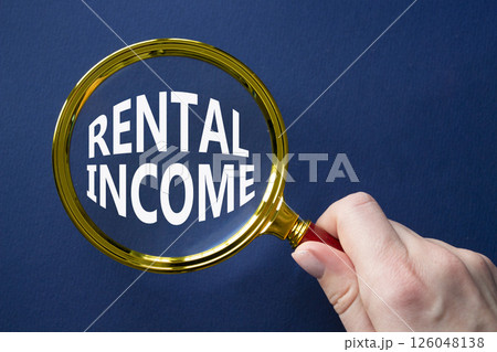 Rental Income symbol. Magnifying glass with words Rental Income. Beautiful deep blue background. Businessman hand. Business and Rental Income concept. Copy space. Rental Income symbol. Magnifying glass with words Rental Income. Beautiful deep blue background. Businessman hand. Business and Rental Income concept. Copy space. 126048138