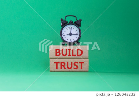 Build trust symbol. Wooden blocks with words Build trust. Beautiful green background with alarm clock. Business and Build trust concept. Copy space. 126048232