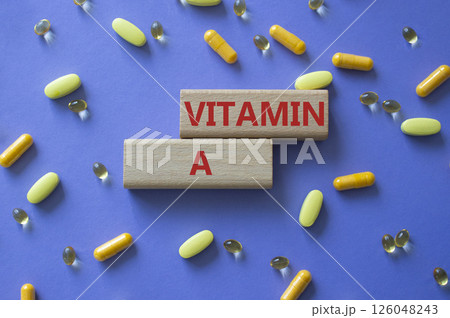 Vitamin A symbol. Concept word Vitamin A on wooden blocks. Beautiful purple background with pills. Medicine and Vitamin A concept. Copy space 126048243