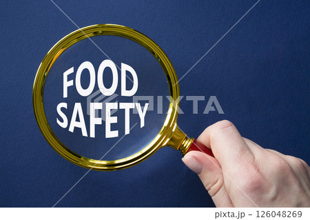 Food Safety symbol. Magnifying glass with words Food Safety. Beautiful deep blue background. Businessman hand. Business and Food Safety concept. Copy space. Food Safety symbol. Magnifying glass with words Food Safety. Beautiful deep blue background. Businessman hand. Business and Food Safety concept. Copy space. 126048269