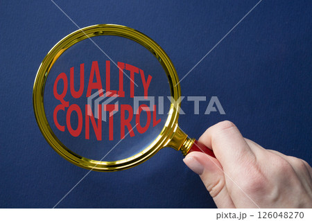 Quality Control symbol. Magnifying glass with words Quality Control. Beautiful deep blue background. Businessman hand. Business and Quality Control concept. Copy space. 126048270