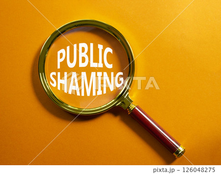 Public Shaming symbol. Magnifying glass with words Public Shaming. Beautiful orange background. Business and Public Shaming concept. Copy space. Public Shaming symbol. Magnifying glass with words Public Shaming. Beautiful orange background. Business and Public Shaming concept. Copy space. 126048275