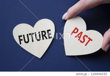 Future or Past symbol. Concept word Future or Past on wooden hearts. Businessman hand. Beautiful deep blue background. Business and Future or Past concept. Copy space Future or Past symbol. Concept word Future or Past on wooden hearts. Businessman hand. Beautiful deep blue background. Business and Future or Past concept. Copy space 126048291