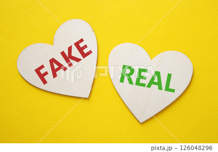 Real or Fake symbol. Concept word Real or Fake on wooden hearts. Beautiful yellow background. Business and Real or Fake concept. Copy space Real or Fake symbol. Concept word Real or Fake on wooden hearts. Beautiful yellow background. Business and Real or Fake concept. Copy space 126048296