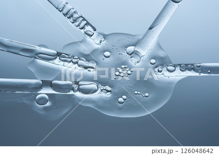 A large drop of hyaluronic serum for a blistered face and several pipettes on a blue background. 126048642
