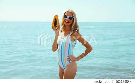 Summer, happy smiling young woman, laughing, with fruits, having fun on the beach on sea background Summer, happy smiling young woman, laughing, with fruits, having fun on the beach on sea background 126048888