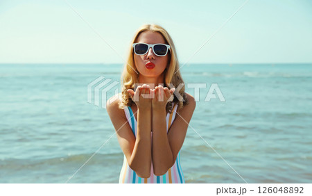 Summer vacation, beautiful young woman blowing kiss in swimsuit, sunglasses, on the beach on sea 126048892