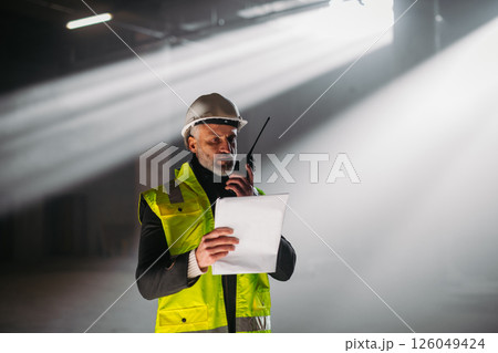 Construction foreman giving instructions over radio during building inspection. 126049424