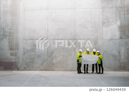 Team of engineers and construction workers reviewing blueprints, building site. Team of engineers and construction workers reviewing blueprints, building site. 126049430