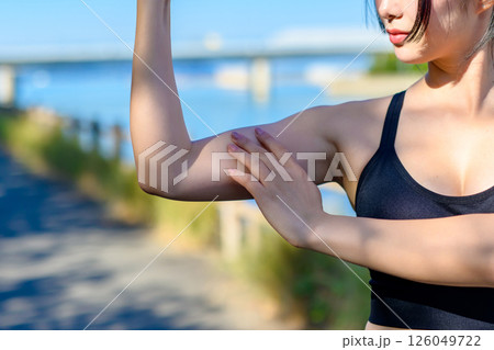 青空の下で運動するかっこいい女性　力こぶ　上腕二頭筋　エクササイズ　運動　自信　トリミングアップ 126049722