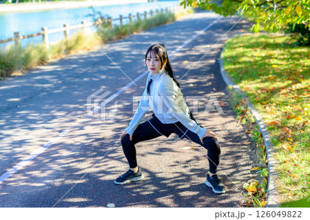 木漏れ日の道でストレッチをするかっこいい女性 準備運動 股割り 股関節 木漏れ日の道でストレッチをするかっこいい女性 準備運動 股割り 股関節 126049822