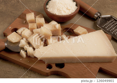 Freshly sliced and grated cheese, parmesan cheese, on a wooden chopping board, rustic style, no people Freshly sliced and grated cheese, parmesan cheese, on a wooden chopping board, rustic style, no people 126049901