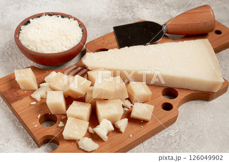 Freshly sliced and grated cheese, parmesan cheese, on a wooden chopping board, rustic style, no people Freshly sliced and grated cheese, parmesan cheese, on a wooden chopping board, rustic style, no people 126049902