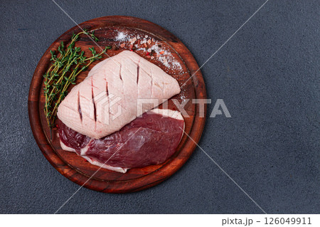 Fresh raw duck breasts, on a wooden chopping board, with herbs and spices, no people Fresh raw duck breasts, on a wooden chopping board, with herbs and spices, no people 126049911