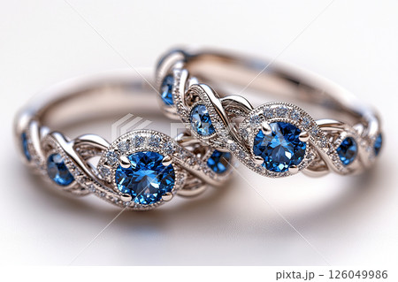 Luxurious pair of wedding rings with blue stones on a white background. Rococo-Renaissance style. 126049986
