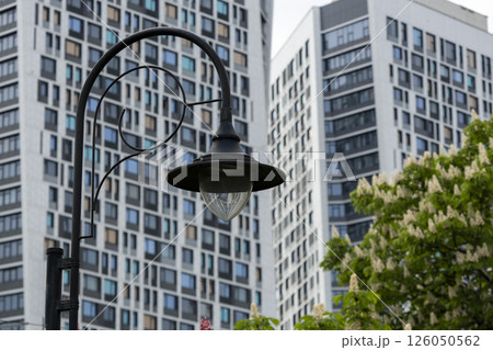 Patterned street lamp against the backdrop of blossoming chestnut trees and high-rise buildings in the background 126050562