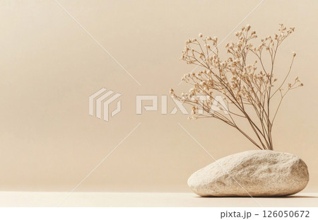 A soothing minimalist setup emphasizes a dried plant on a rock, set against a beige background. This design evokes tranquility and simplicity, perfect for decor inspiration. A soothing minimalist setup emphasizes a dried plant on a rock, set against a beige background. This design evokes tranquility and simplicity, perfect for decor inspiration. 126050672