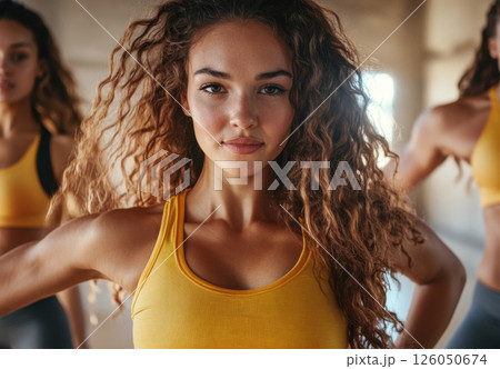 A woman with long, curly hair intensely participates in a high-energy dance class among others. 126050674