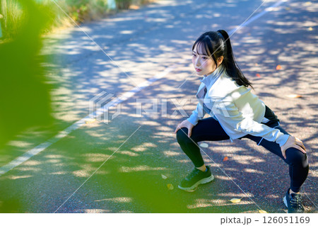 木漏れ日の道でストレッチをするかっこいい女性 準備運動 股割り 股関節 木漏れ日の道でストレッチをするかっこいい女性 準備運動 股割り 股関節 126051169